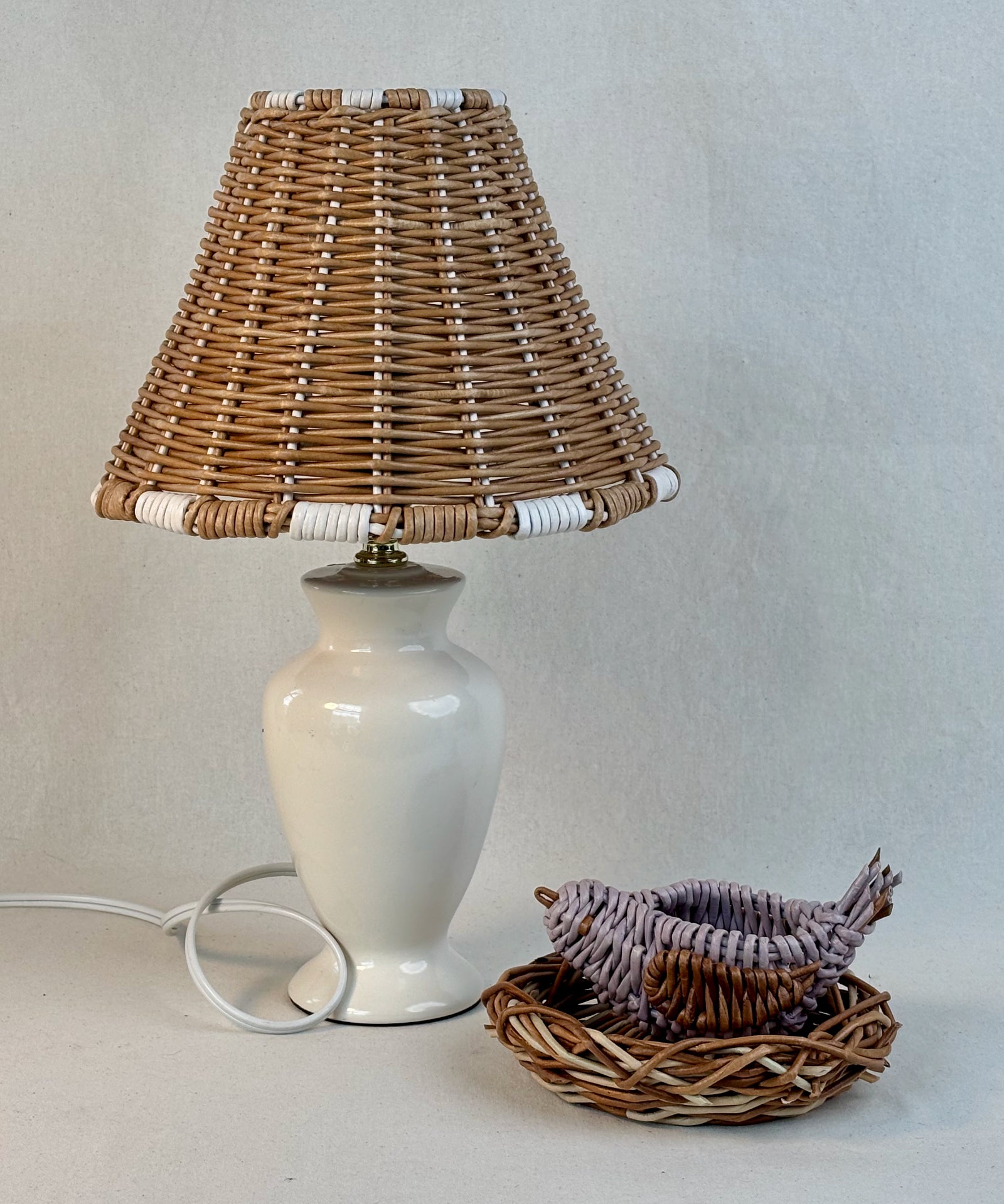 Lamp with a woven paper vine lampshade and a woven decorative bird in a nest