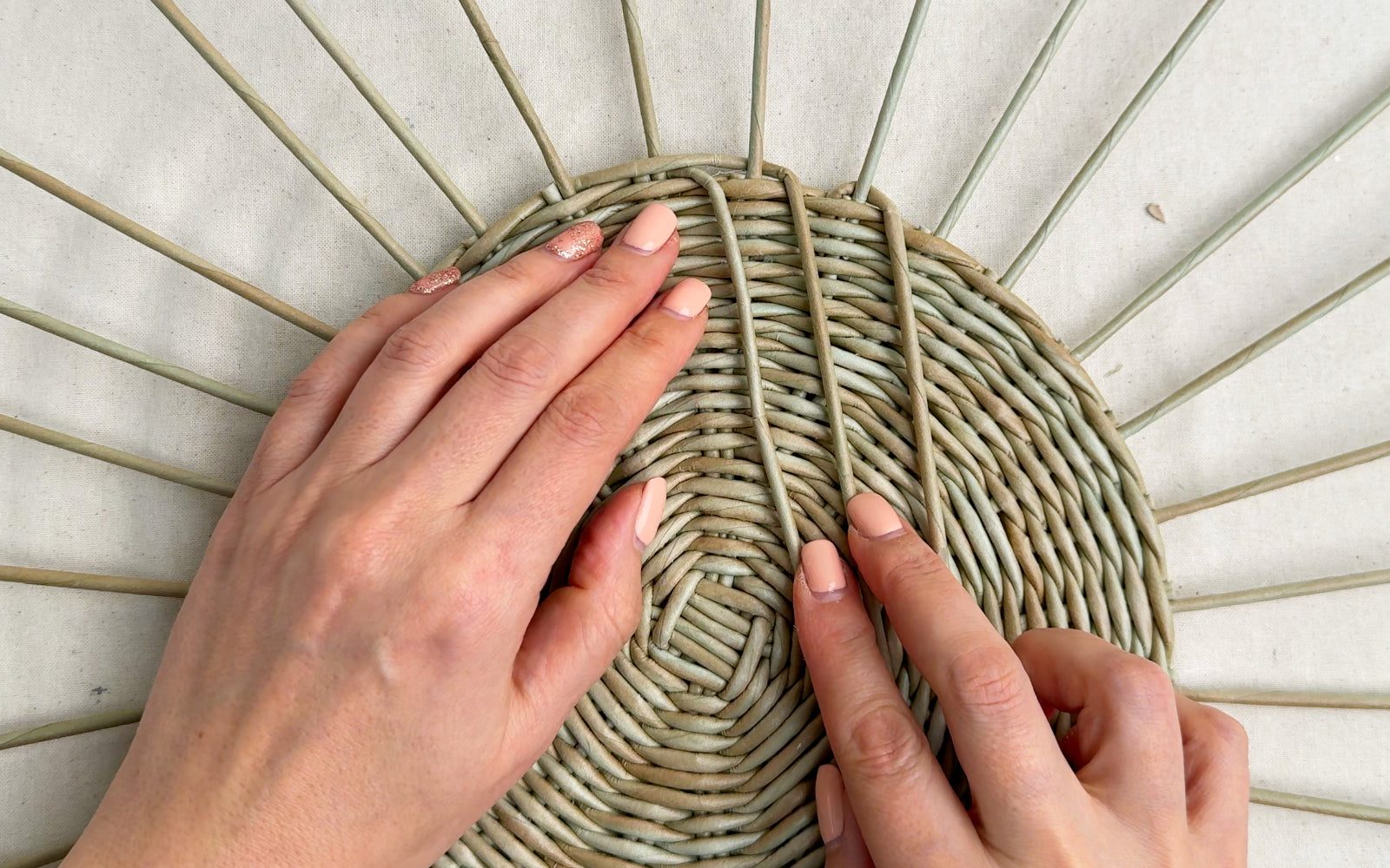 Hands weaving a flat plate from paper vine